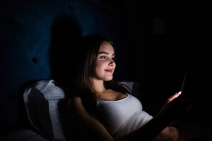 Frau mit Handy im Bett in der Nacht