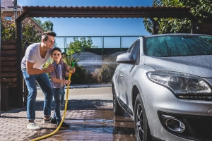Vater und Sohn beim Auto waschen daheim
