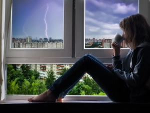 Frau sitzt bei Gewitter in ihrer Wohnung