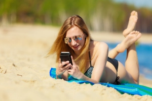 Junge Frau mit Handy am Strand